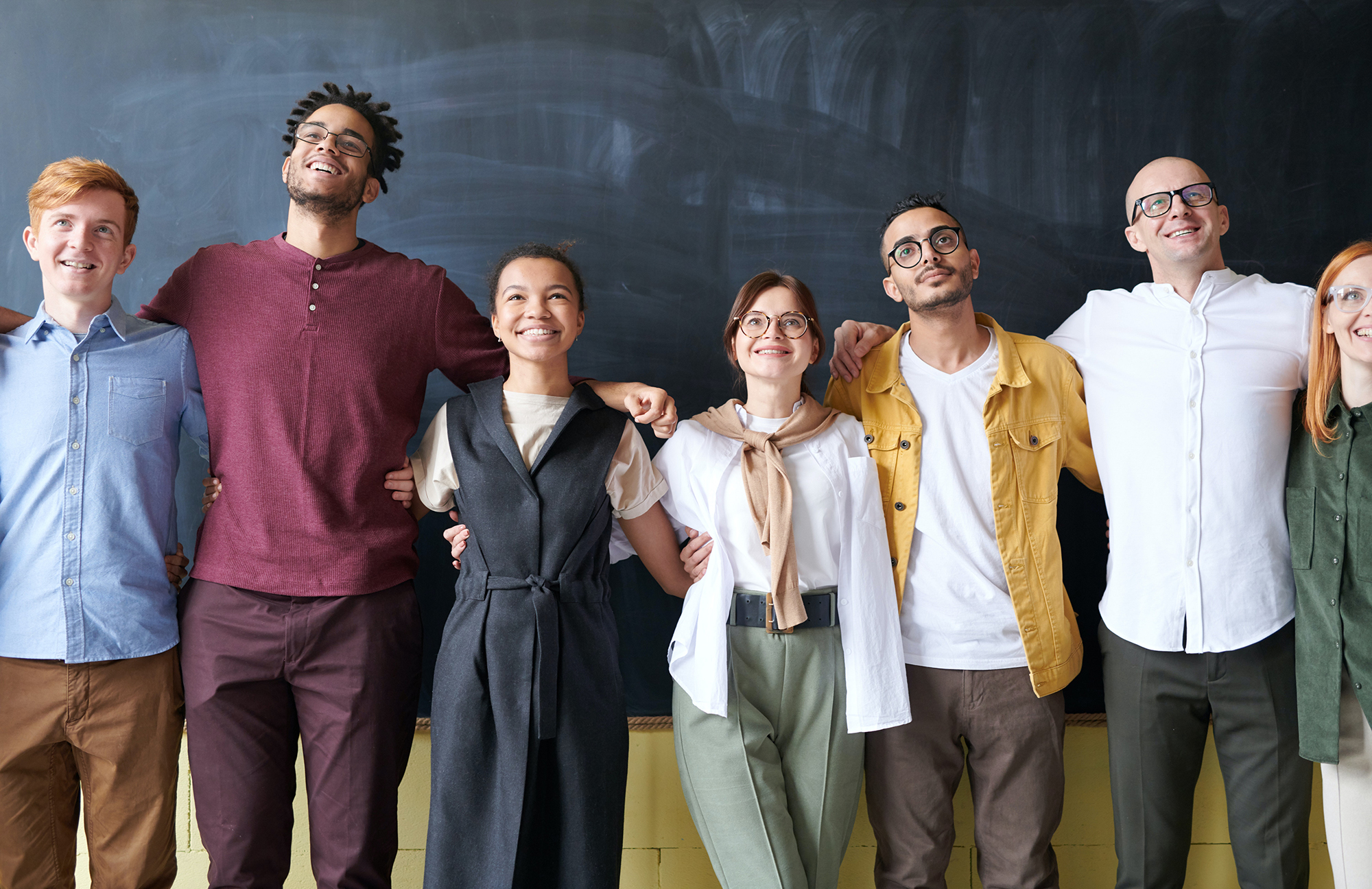Picture: Happy diverse group smiling in front of a chalkboard